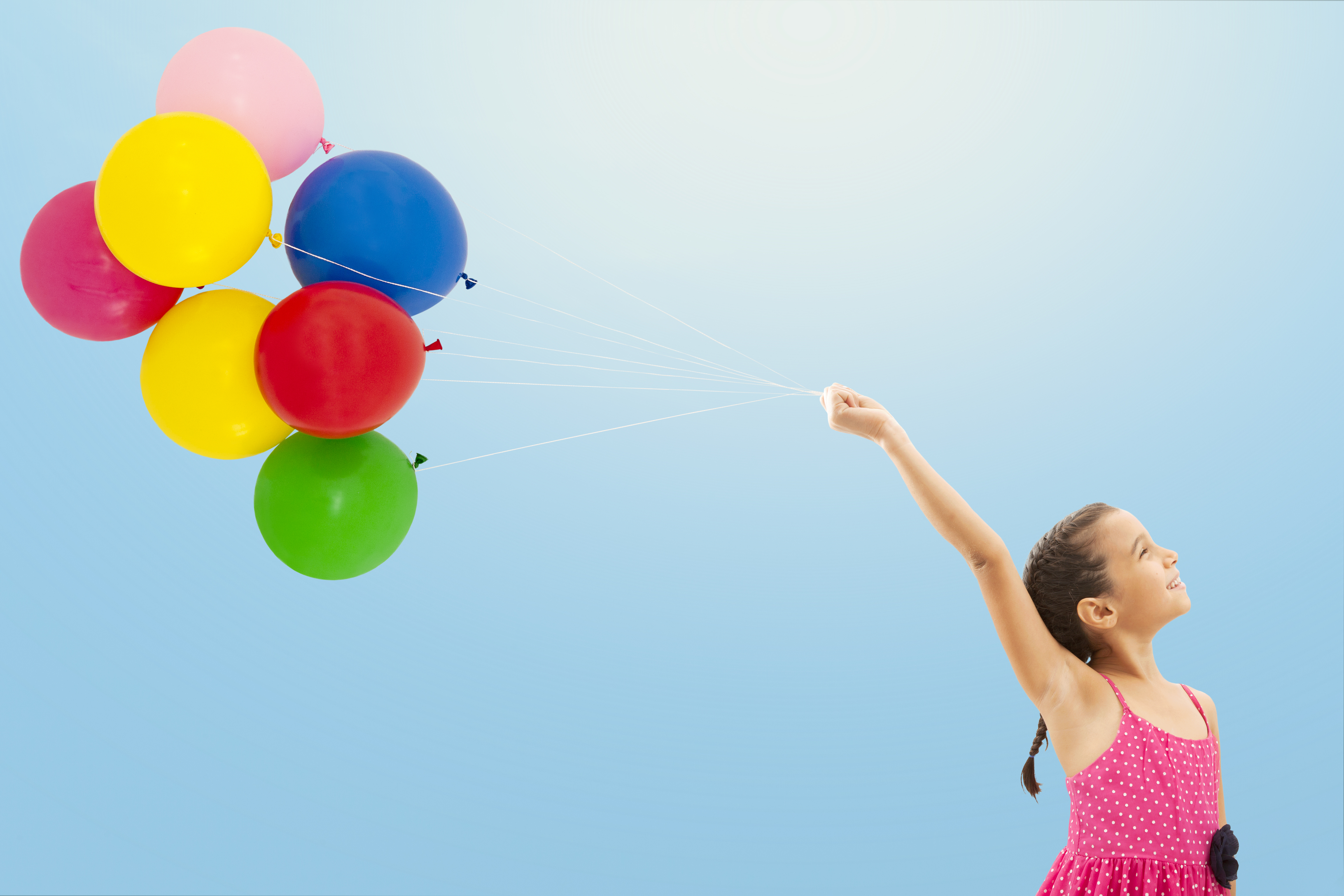 Little girl with balloons on sky background